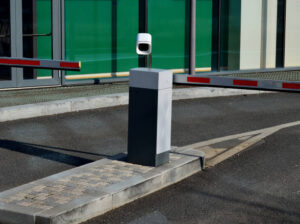 Automated parking lot gate barrier with a license plate recognition camera, controlling vehicle access to a secured building entrance.