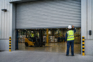 Industrial warehouse with workers operating a rolling shutter door for controlled access and goods movement.